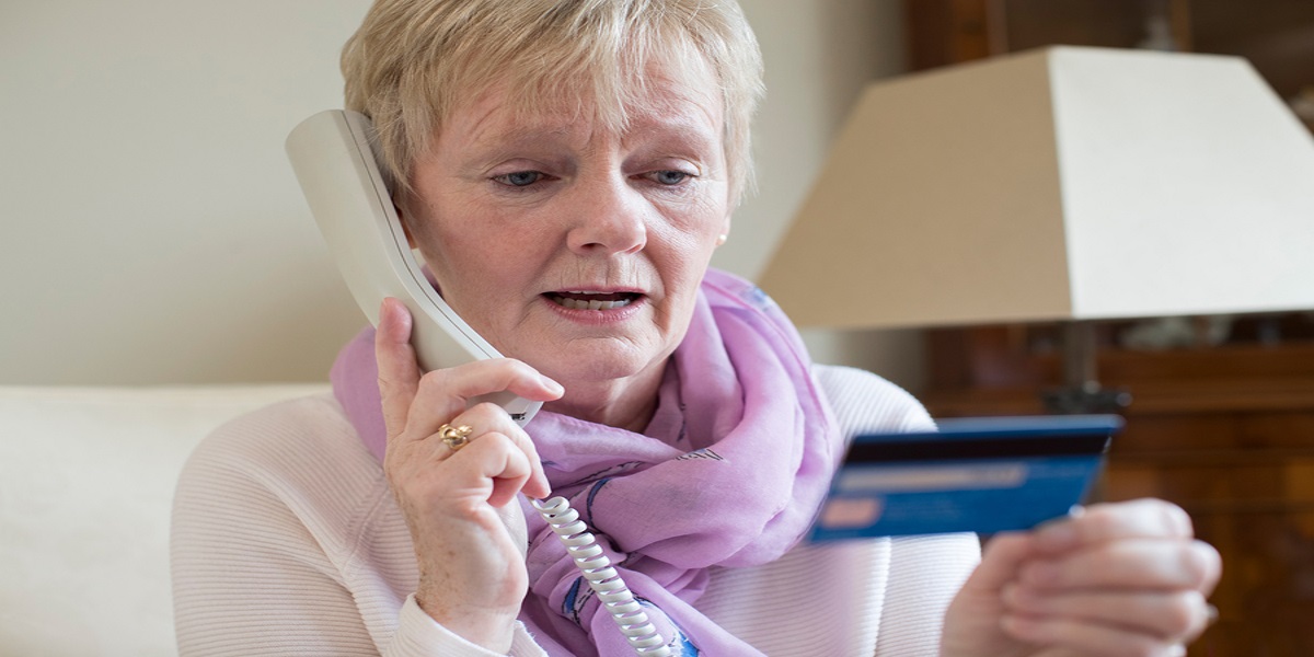 confusing tax system helping fraudsters. Shown by photo of a confused woman on the phone giving her bank card details.