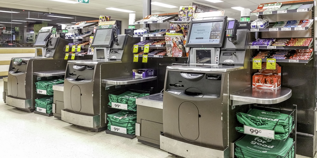 Photo of three self service checkouts in an Australian Woolworths. Illustrating the proposed new 1p tax on self service checkout use to fund intergenerational development projects.