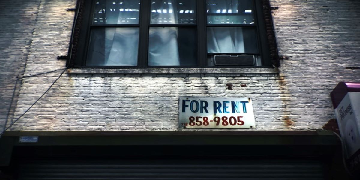 Showing first floor window of a brick building with a 'For Rent' sign underneath it.