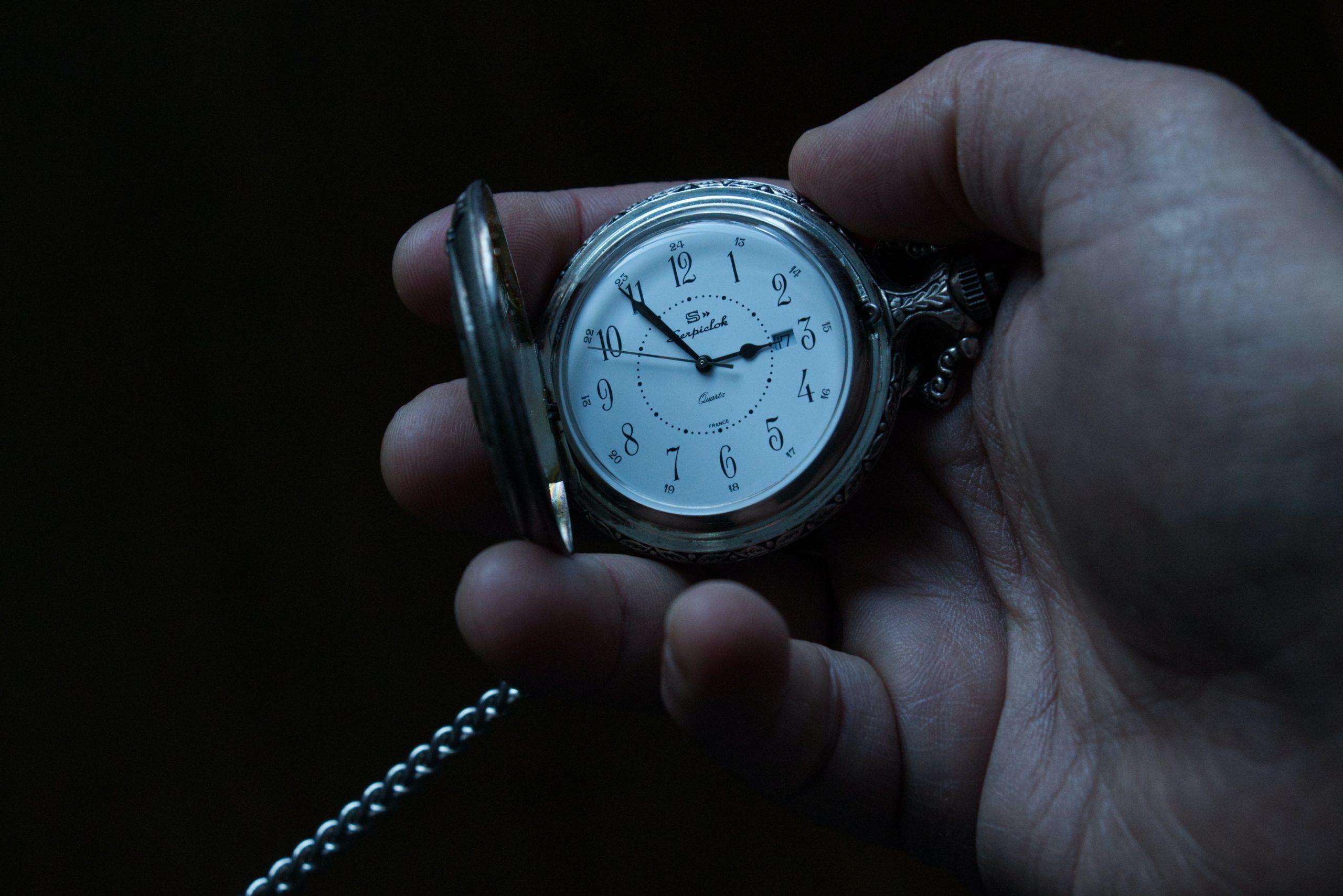 Pocket watch being held open in a white man's hand.