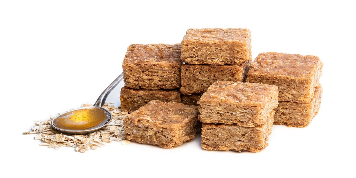 Pile of traditional flapjacks, which are zero rated for VAT, beside a spoon of golden syrup.